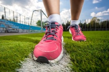 Closeup photo of pink female sneakers on soccer grass field