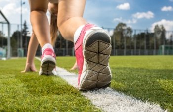 Closeup shot of woman in sneakers standing on white line drawn on grass