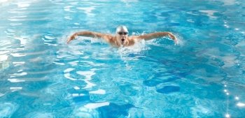 Young handsome athlete swimming in poll at butterfly style