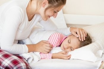 Portrait of smiling young mother holding hand on sleeping daughters head
