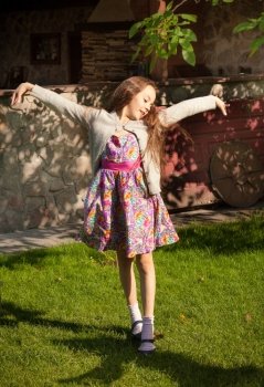 Cute young girl stretching and dancing at yard