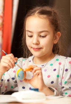 Portrait of girl painting traditional easter eggs at home