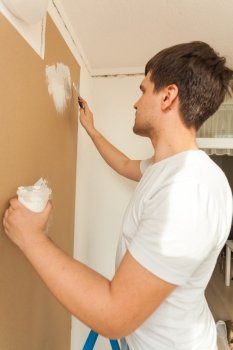 Closeup portrait of young man aligning wall with putty