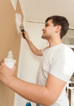 Closeup portrait of man working with spatula and putty on gypsum cardboard wal
