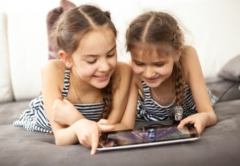 Portrait of two smiling girls pointing at touchscreen of tablet
