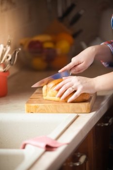 Closeup photo of woman cutting bread on wooden desk