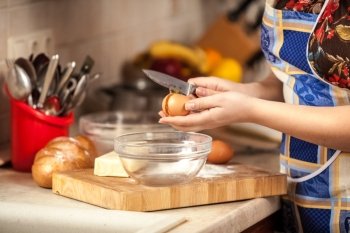 Closeup photo of housewife cracking egg with knife