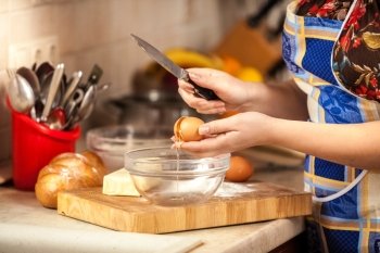 Closeup photo of woman cracking egg with knife