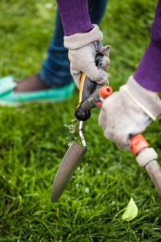 Closeup photo of gardener cleaning small garden shovel with water
