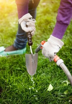Closeup photo of woman cleaning garden tool with hosepipe