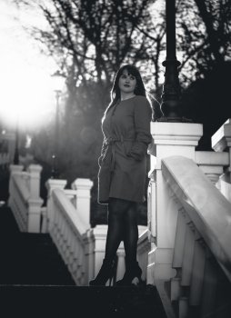 Black and white photo of elegant woman posing on stairs at park at sunny day