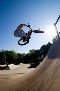 Bmx rider performing a bar spin to a quarter pipe ramp on a skatepark.