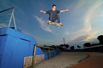 Skateboarder flying over a ramp on sunset at the local skatepark.