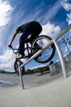 Biker doing double peg grind down the hand rail over the stairs