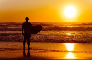Surfer watching the waves at sunset in Portugal.