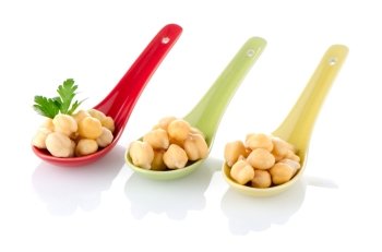 chickpeas over ceramic spoons on white background.
