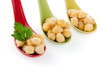 chickpeas over ceramic spoons on white background.