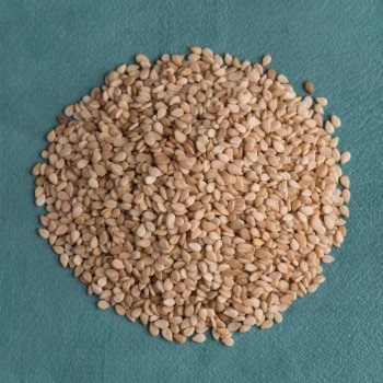 Top view of sesame seeds against blue vinyl background.