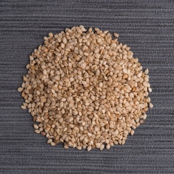 Top view of sesame seeds against grey vinyl background.