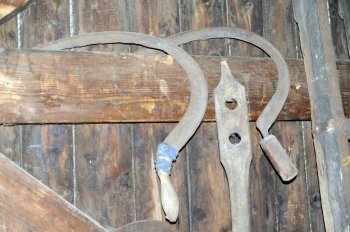 old scythes hanging at a wooden plank