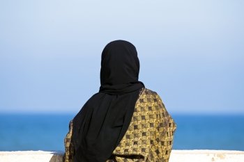 Arab woman with Islamic headscarf looking over the ocean