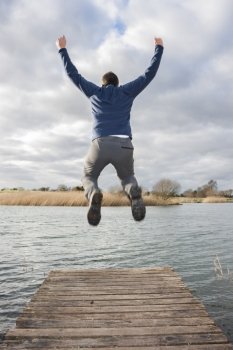 Young adult jumping on the edge of a dock