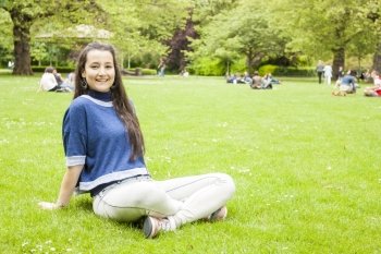 Beautiful woman sitting on the grass looking at camera