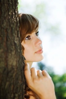 attractive girl leaning against a tree. outdoor shot