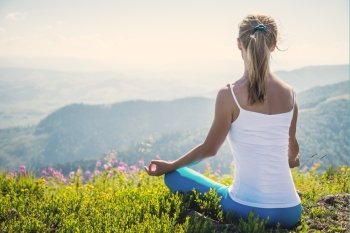Young woman meditate on the top of mountain in sunrise time