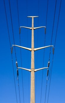 Single concrete electrical tower with cables and insulators against blue sky.