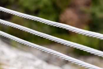 Close-up of three parallel metal cables on blurred background.