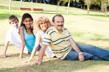Young family relaxing in park and smiling at camera.