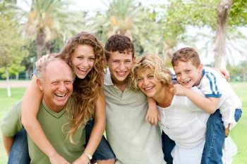 Granparents giving piggy-ride to young generation as they smile at camera