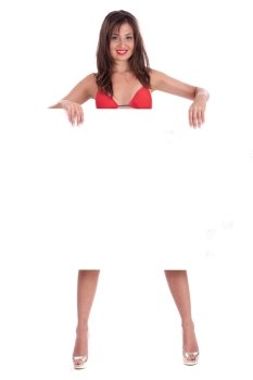 Young smiling woman in red bikini holding white blank board over white background