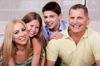 Affectionate family of four smiling at camera and having fun