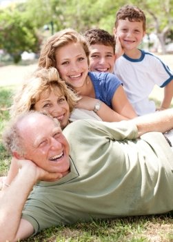 Multi-generation family relaxing in park on sunny day and smiling at camera