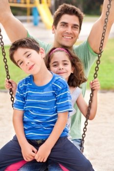 kids having fun with their father in the park and smiling at camera