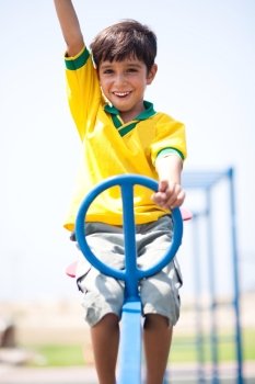 Boy in soccer uniform playing in the park and taking ride on swing