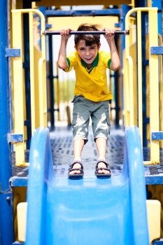 Young school boy sliding down the swing and having fun