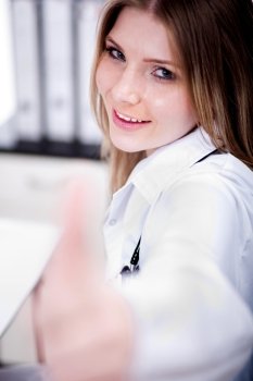 Happy young female doctor showing thumbs up sign