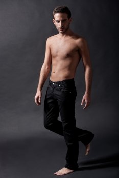 Fashion male model with black jean over black background
