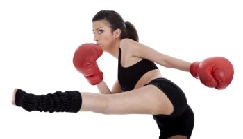 Kickboxing girl giving strong kick with her leg over white background