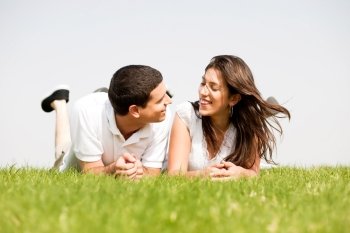 young couple smiling by laying down in a green grass field,outdoor