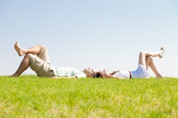 young couple lie down on grass, outdoor at park..