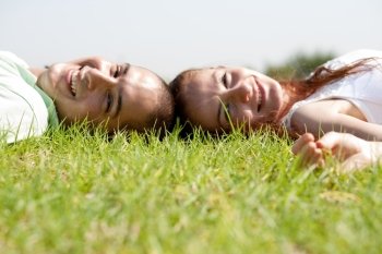 A young couple laying down and relaxing on a  grass lawn