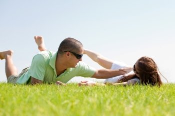 Young man playing with his wife on a grass lawn and laying down