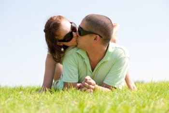 beautiful young Couple lie down on grass and kiss