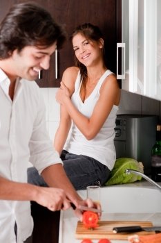 boyfriend sliceing tomottos with his girlfriend in kitchen..