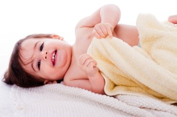 Little smiling baby lying in white towel and wrapped with yellow towel in a white background