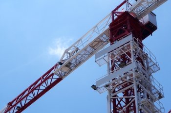 Building crane and building under construction against blue sky. Building crane